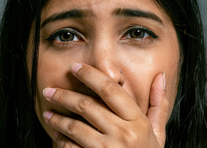 Close-up of a distressed woman covering her mouth, reflecting feelings of being a husband’s second choice and backup. Close-up of a distressed woman covering her mouth, reflecting feelings of being a husband’s second choice and backup.