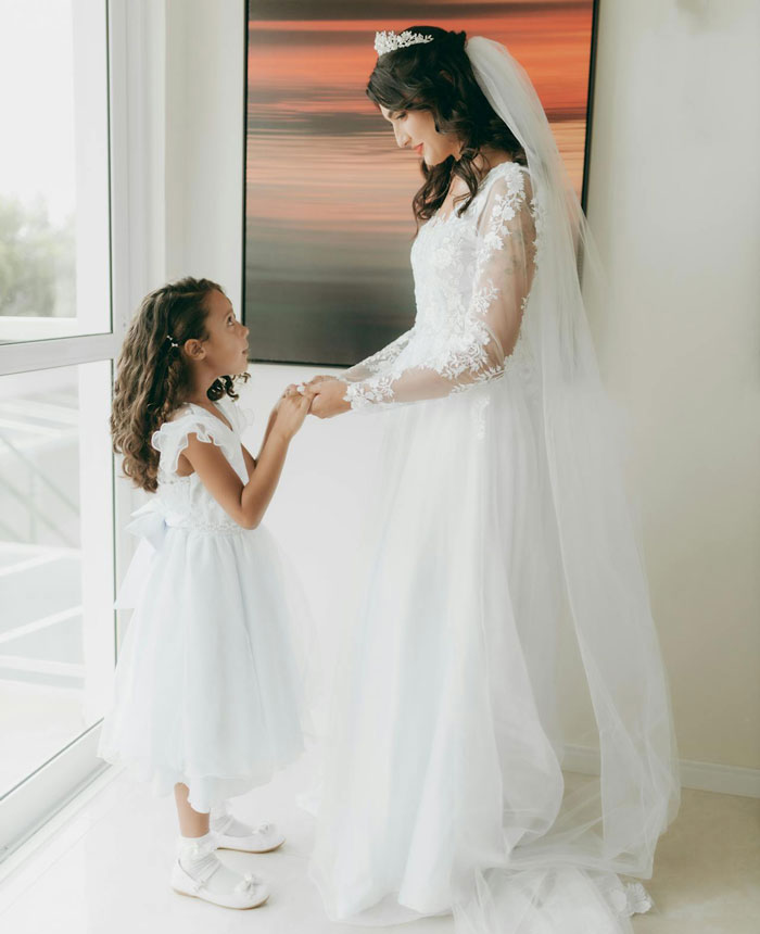 Bride in a wedding dress holding hands with a young girl, depicting woman accused of abandoning husband’s kids. Bride in a wedding dress holding hands with a young girl, depicting woman accused of abandoning husband’s kids.