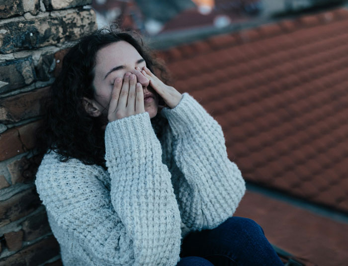 Young woman stressed and upset sitting alone against a brick wall, reflecting struggles in a toxic marriage and family issues. Young woman stressed and upset sitting alone against a brick wall, reflecting struggles in a toxic marriage and family issues.