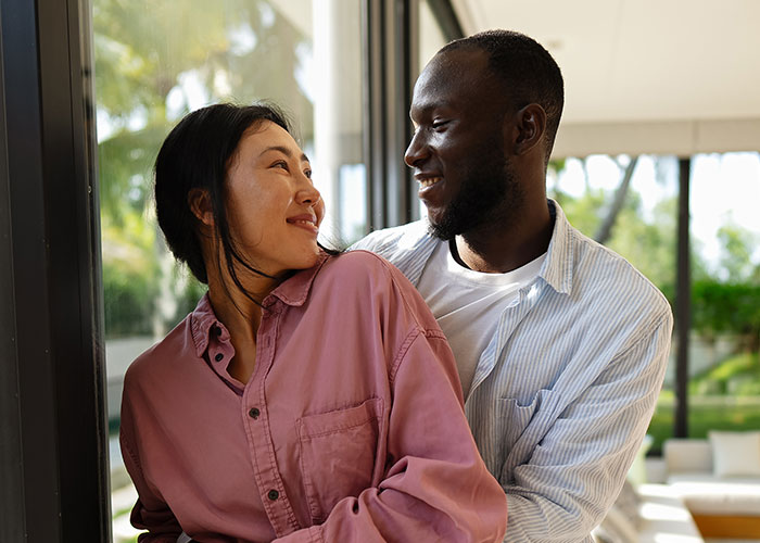 Woman and man smiling at each other indoors, depicting a family conflict involving a woman forbidding brother-in-law contact.