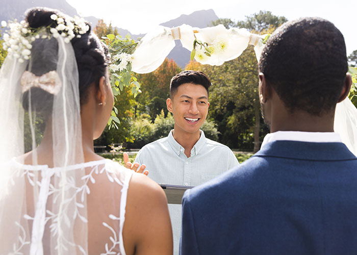 Bride and groom standing before officiant outdoors, representing woman forbidding brother-in-law contact despite seeing nephew less.