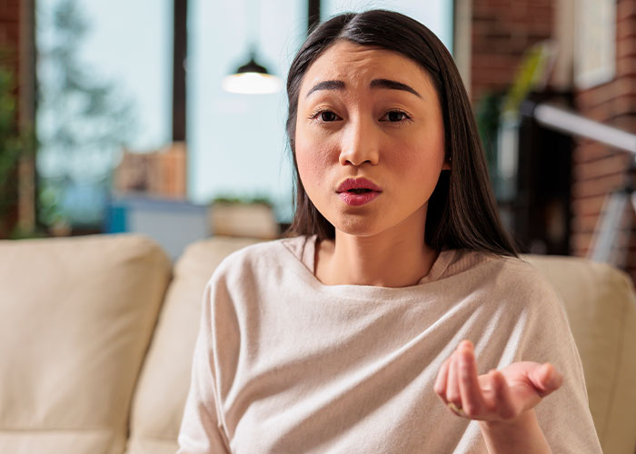Woman forbids brother-in-law from talking to her, risking seeing nephew less, with a serious and frustrated expression indoors.