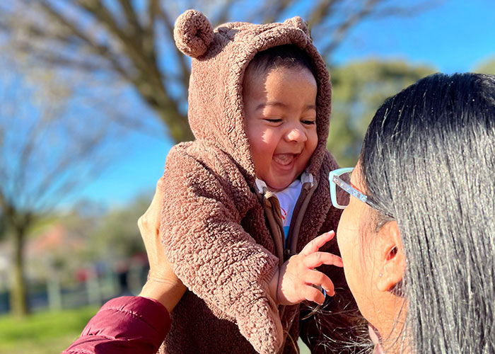 Woman holding smiling baby nephew outdoors, highlighting family tension with brother-in-law over limited contact.