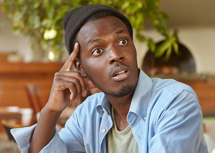 Man in casual clothes and a beanie looking surprised while sitting indoors, reflecting on woman forbidding BIL contact.