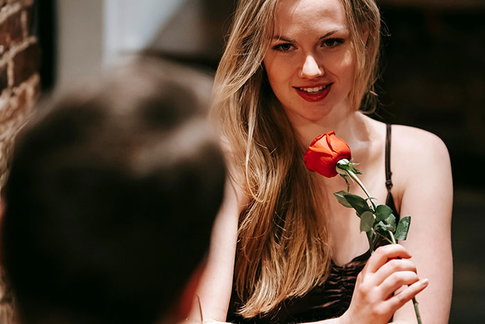 Woman holding a red rose on a date, contemplating her plans for artificial insemination and motherhood.