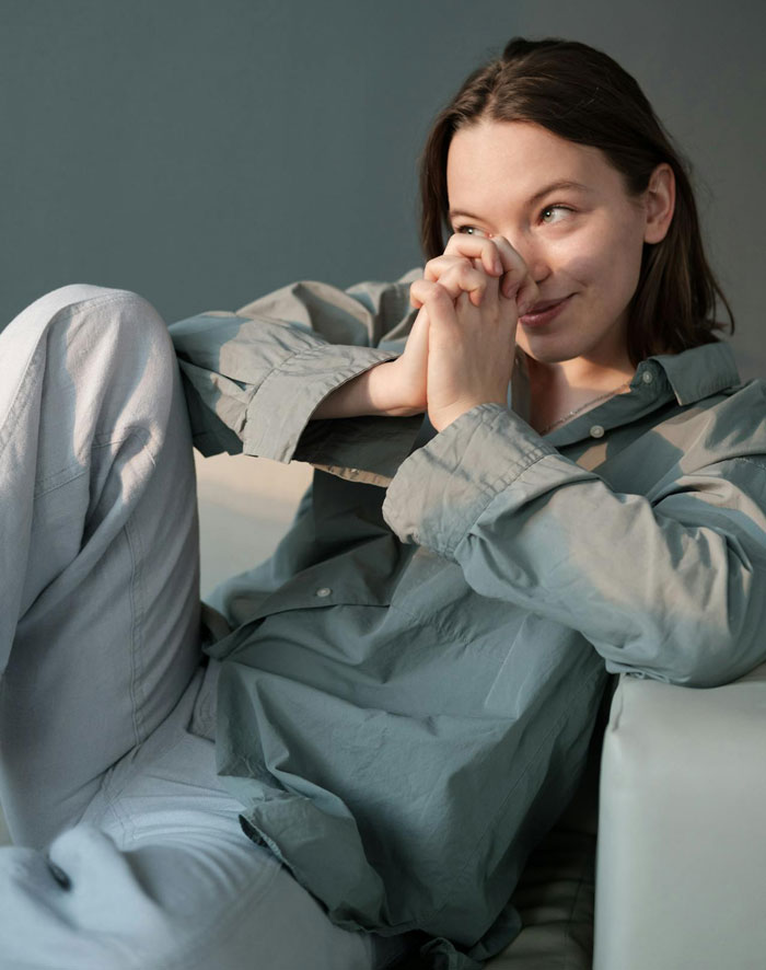 Young woman sitting and smiling thoughtfully, illustrating a woman accusing homeowners of ruining her party by not leaving.