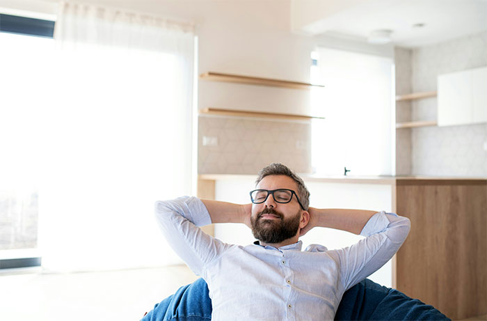 Man with glasses relaxing on a bean bag chair in a bright modern living room after living with women experiences