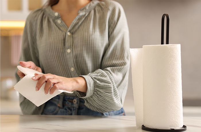 Woman in a striped shirt holding a paper towel in a kitchen, illustrating revelations after living with men.