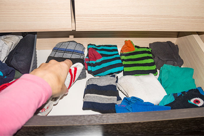 Hand reaching into drawer full of colorful men's socks, illustrating life living with men and shared revelations.