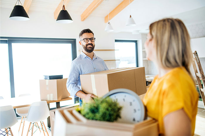Man and woman carrying boxes in a bright modern home, illustrating insights from women living with men experiences.
