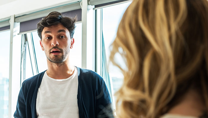 Man reacting with surprise to rage-baits from woman, illustrating impact of words that can ruin a man’s day.