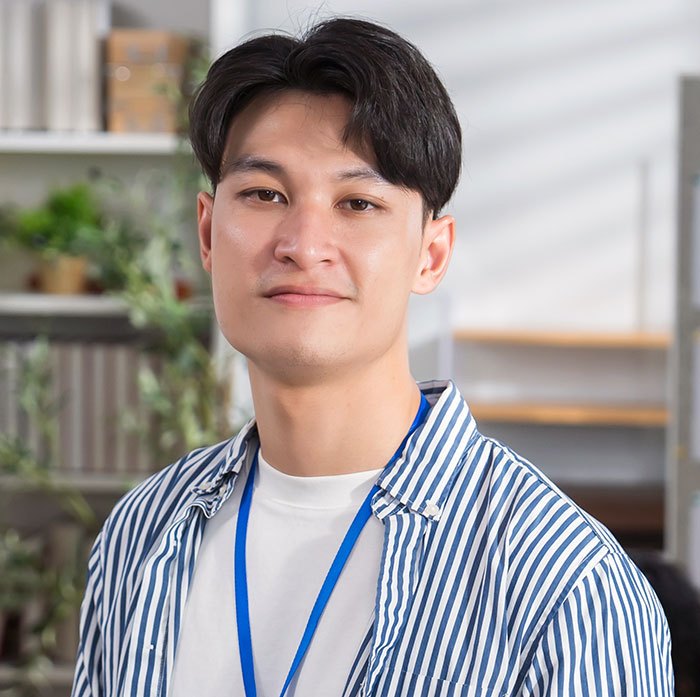 Young man indoors wearing a striped shirt and lanyard, representing emotions related to rage-baits from women.