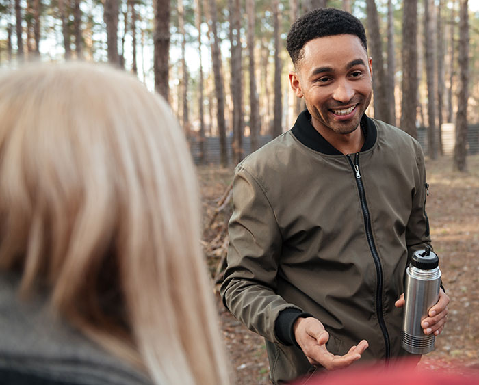 Man smiling and talking outdoors with a woman, illustrating rage-baits that can ruin a man’s day in casual conversation.
