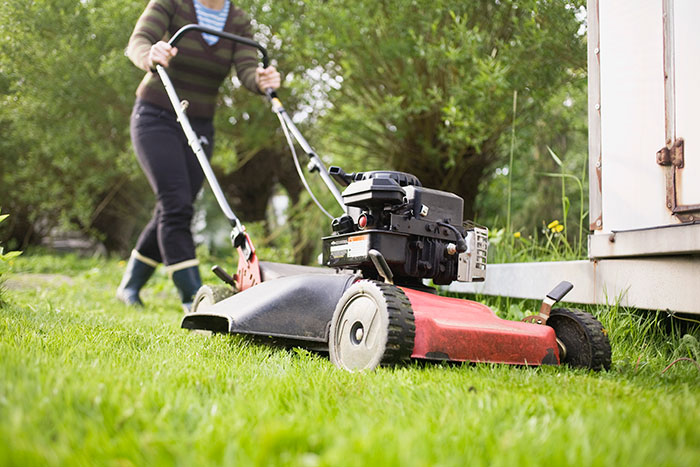Woman using a lawn mower in a garden, illustrating rage-baits from women who know what to say to ruin a man’s day.