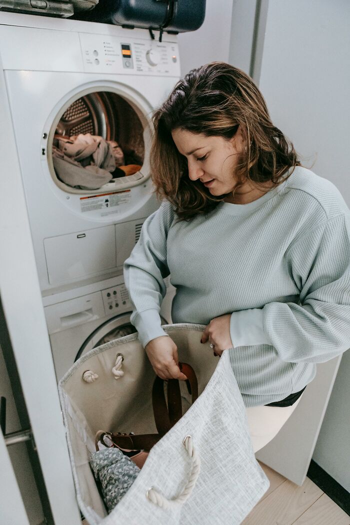Woman doing laundry in front of washer and dryer, illustrating common household grumpy and annoyed mankeeping moments.