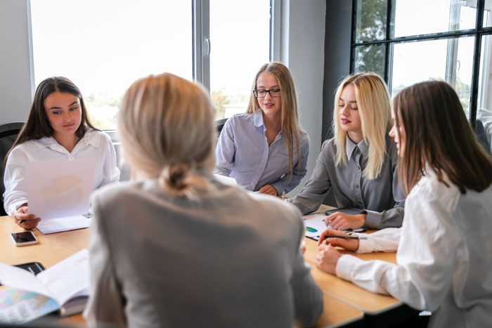 Employees in a meeting room discussing work, illustrating themes of employee sidelining and corporate spying on staff.