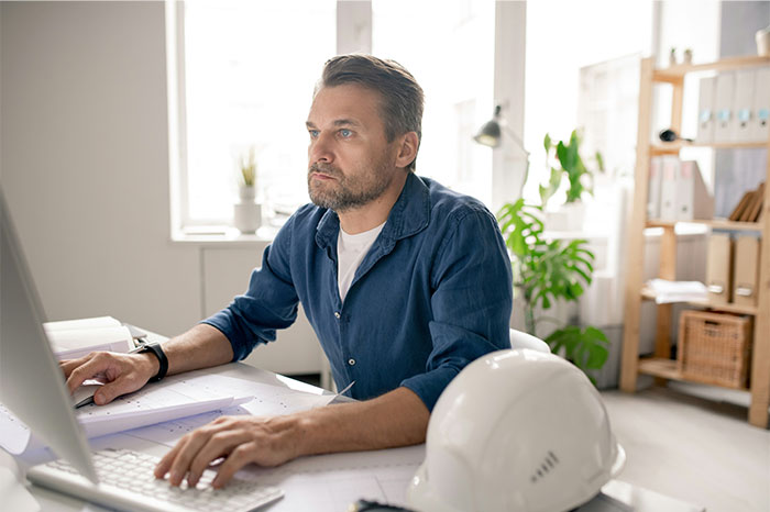 Man working at desk in office, focused and thoughtful, illustrating office Karen can't mind her own business theme. Man working at desk in office, focused and thoughtful, illustrating office Karen can't mind her own business theme.