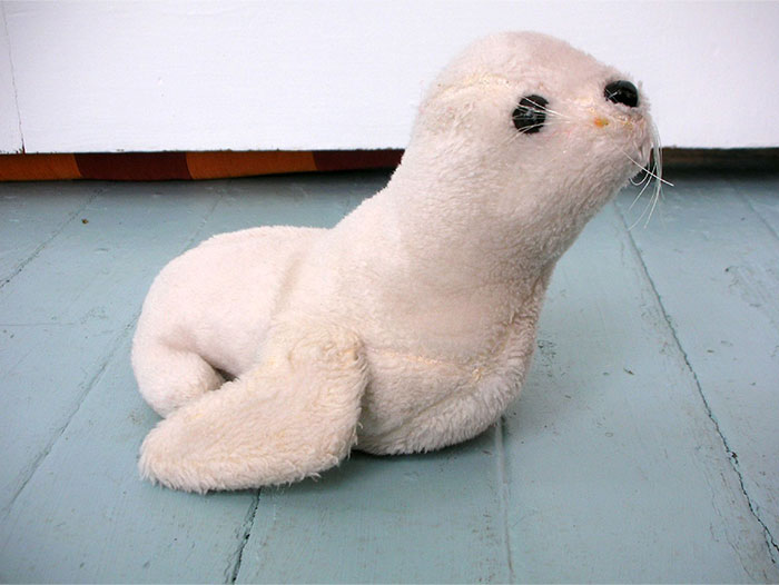 Plush seal toy on wooden floor, symbolizing unusual ways people got permanently banned from a friend’s house.