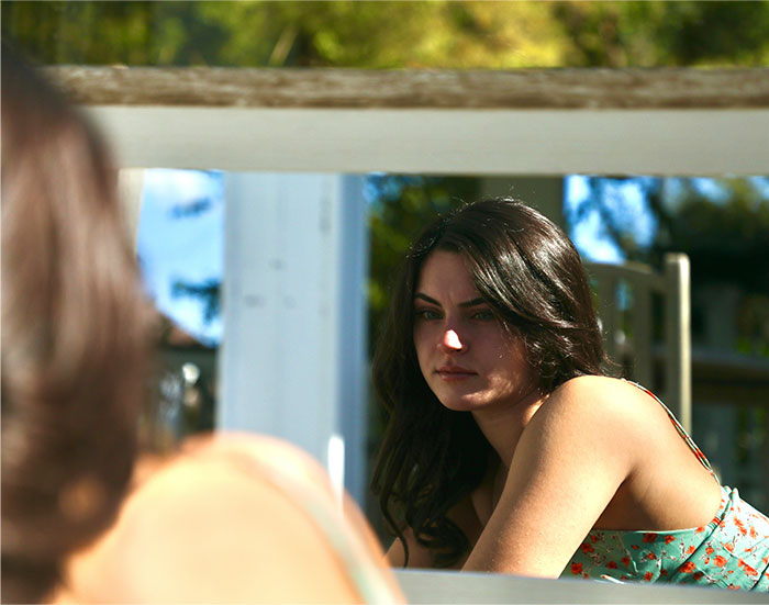 Young woman sitting outdoors, looking serious and reflective, illustrating reasons people got permanently banned from a friend’s house.