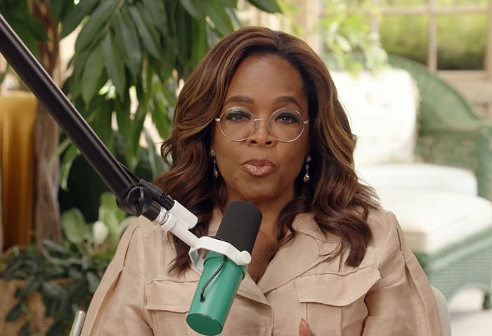 Woman with glasses speaking into a microphone, surrounded by plants, depicting people badly messed up at work stories.
