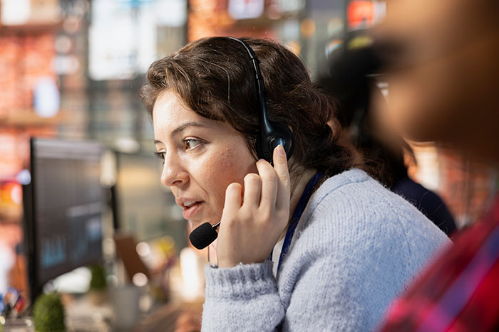 Customer support representative wearing headset and handling a work issue, illustrating people messing up at work stories.