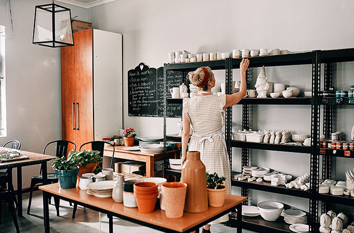 Woman organizing ceramic pottery on shelves in a workshop, illustrating workplace mishaps and how people managed to recover.