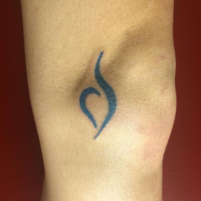 Simple blue abstract tattoo on skin, showing a common challenge faced by tattoo artists with difficult clients.