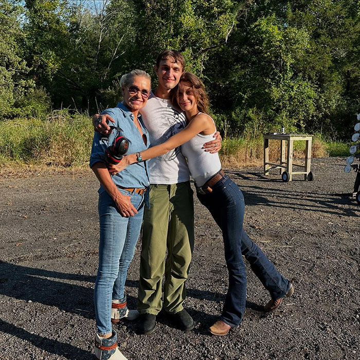 Bella Hadid with two people outdoors, sharing a warm embrace after revealing years of invisible suffering.