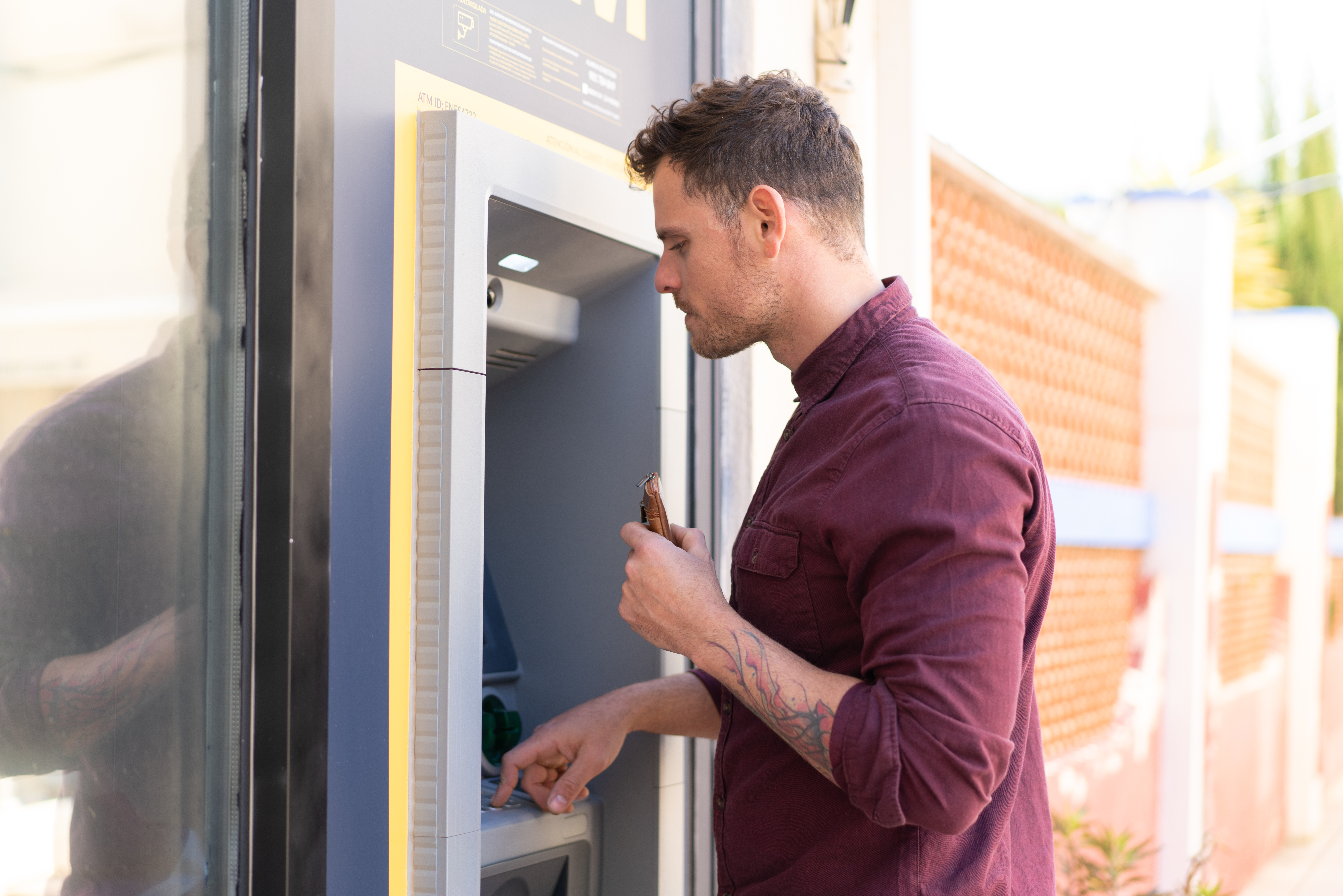 Man using ATM machine outdoors, illustrating bank funds access issue and impact on social media from Russian bots.