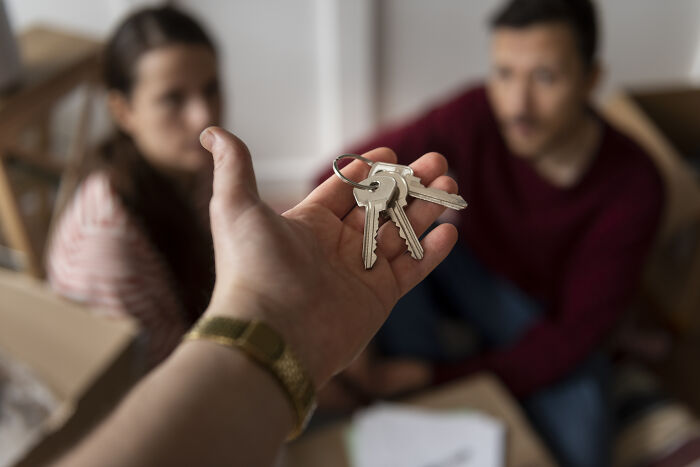 Hand holding keys in front of a couple, symbolizing real-life hexes curses and spells linked to witchcraft beliefs.