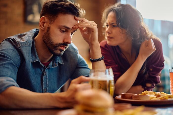 Young man looking upset while woman talks to him, illustrating dumbest and out of touch things people have been told.