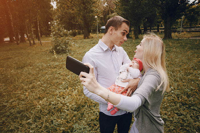 Young siblings taking a selfie outdoors with a baby, capturing a moment of family and adoption connection.