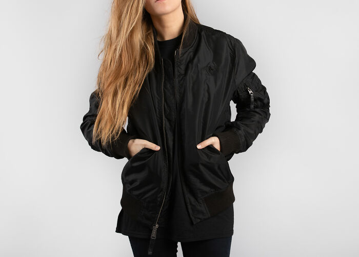 Woman with long blonde hair wearing a black bomber jacket with hands in pockets, illustrating unusual rules people grew up with.