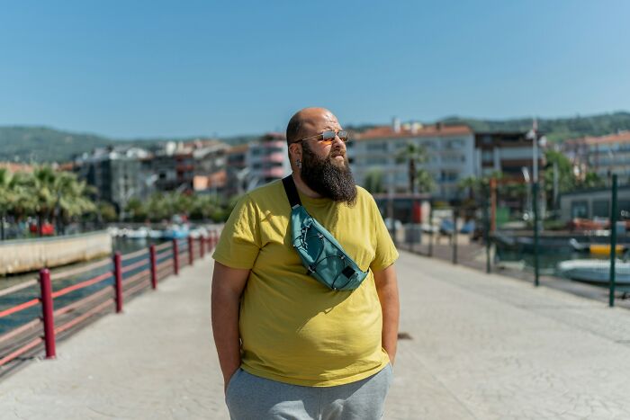Man in sunglasses and a yellow shirt standing outdoors by the water, illustrating opinions on kaomojis and cultural appropriation.