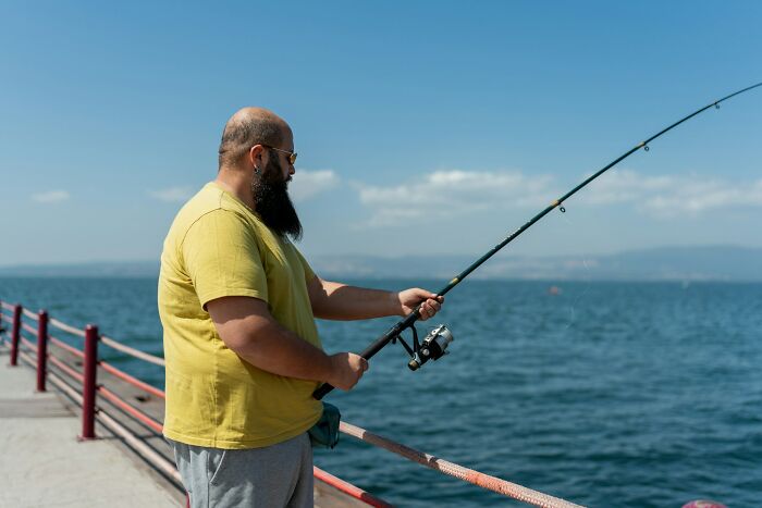 Man with sunglasses fishing on a pier by the water, illustrating Americans finding a loophole and using it.