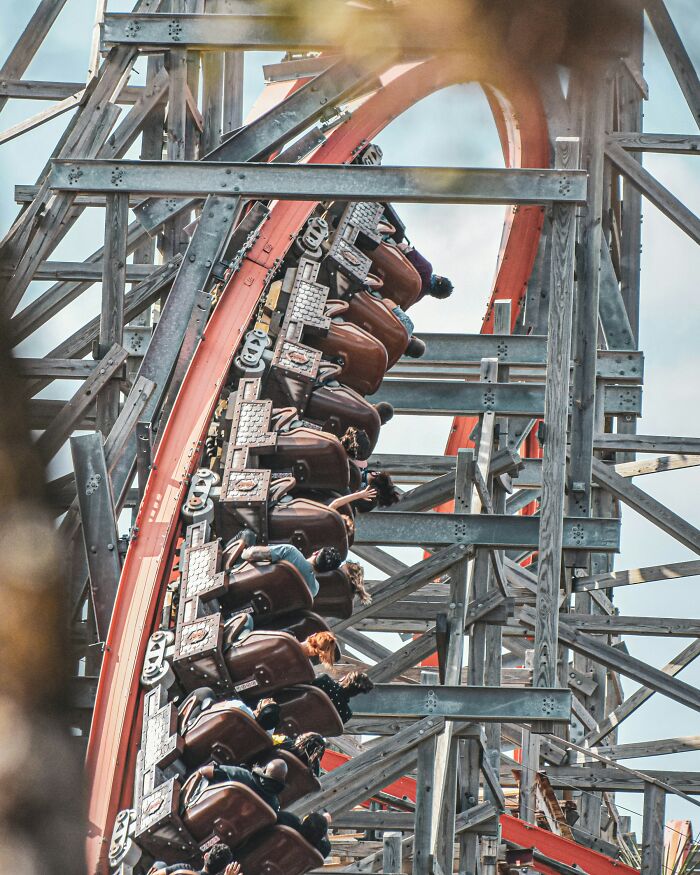 Roller coaster riders leaning into the sharp turn on a wooden track, showing moments of thrill and loophole excitement.
