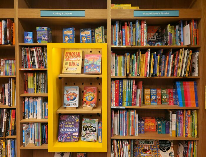 Bookshelves filled with coding, circuits, study guides, and puzzles in a children's bookstore section.