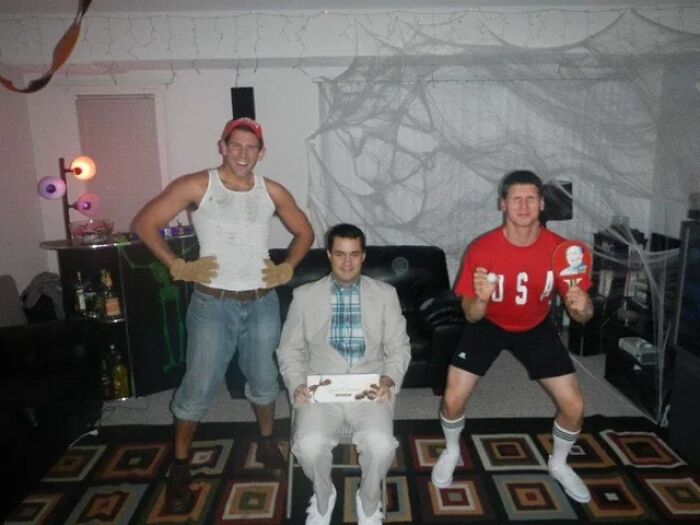 Three men in costumes indoors, one seated dressed as Forrest Gump, showcasing Tom Hanks transformation cosplay.