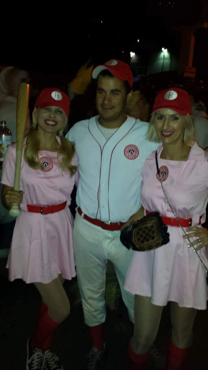 Three people dressed in iconic baseball uniforms, inspired by characters linked to Tom Hanks movies at a night event.