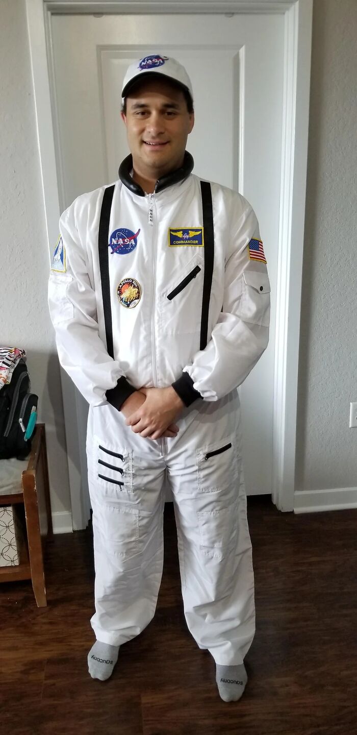 Man dressed as astronaut, part of 14 years transforming into the many faces of Tom Hanks, standing indoors.