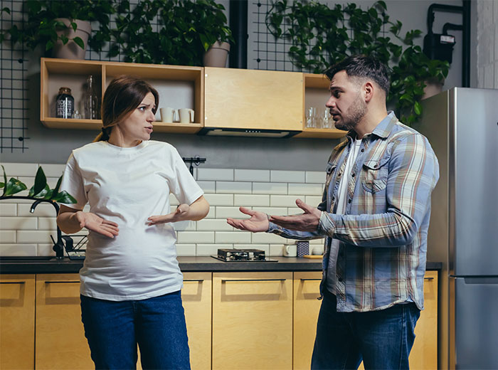 Pregnant woman and man in kitchen having a serious conversation about male best friend stepping into father role.