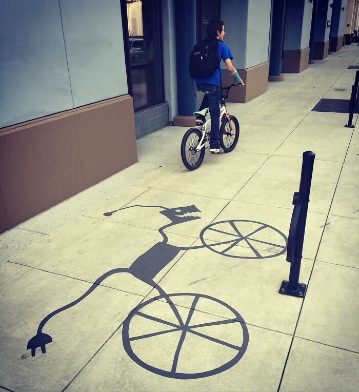 Bicycle casting clever shadow art installation on sidewalk, transforming ordinary objects into creative shadow art.