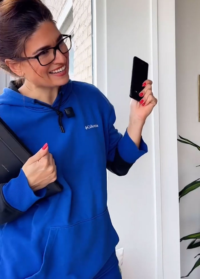 A woman wearing glasses and a blue hoodie holds a phone and a tablet, smiling indoors, illustrating cultural food sharing differences. A woman wearing glasses and a blue hoodie holds a phone and a tablet, smiling indoors, illustrating cultural food sharing differences.