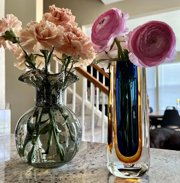 Two unique vintage glass vases with fresh flowers, showcasing thrift store jackpot finds on a kitchen countertop.