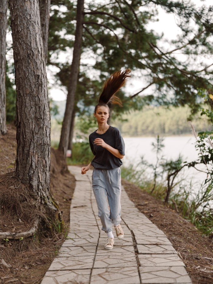 Teen girl running on a forest path near water, representing parents lied about food allergies causing no contact with daughter.