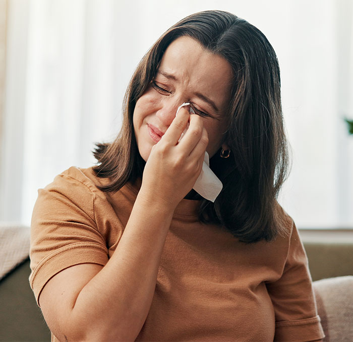 Woman wiping tears from her eyes, expressing sadness after hearing husband admit she is ugly in a personal moment.