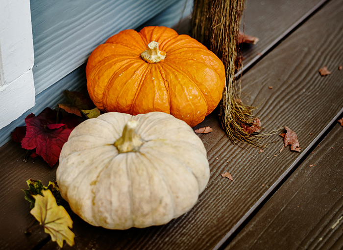 Rotting pumpkin on a wooden porch with autumn leaves, reflecting a neighbor's neglected seasonal decoration.