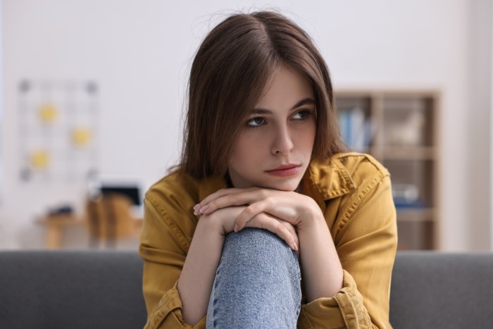 Teenage girl looking thoughtful and upset while sitting alone, reflecting on parents lied food allergies no contact situation.