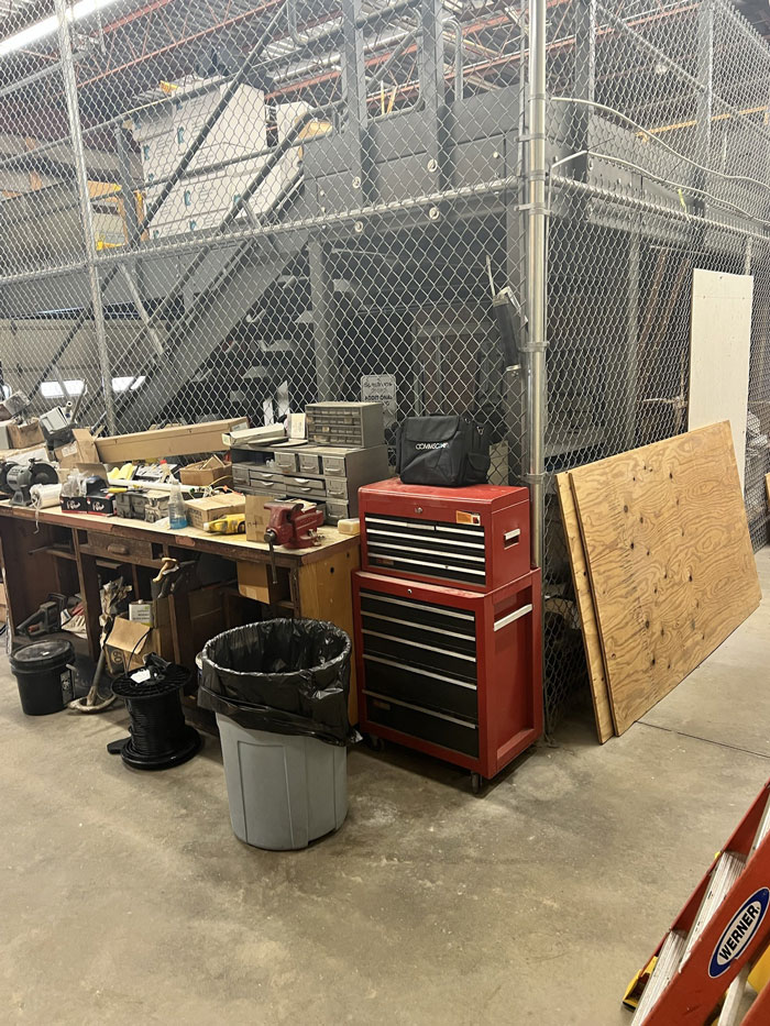 Workshop area with red tool chest and cleaning supplies, part of a coworker&rsquo;s office frozen in grime cleanup task