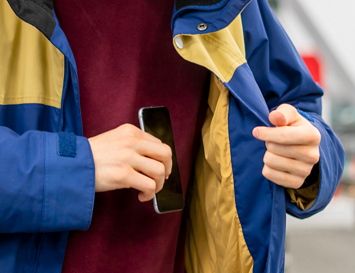 Employee holding phone inside jacket pocket, highlighting moment of overhearing and calling out in a public setting.